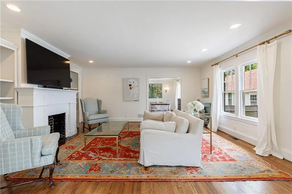 Living area with wood finished floors, baseboards, recessed lighting, a fireplace, and crown molding