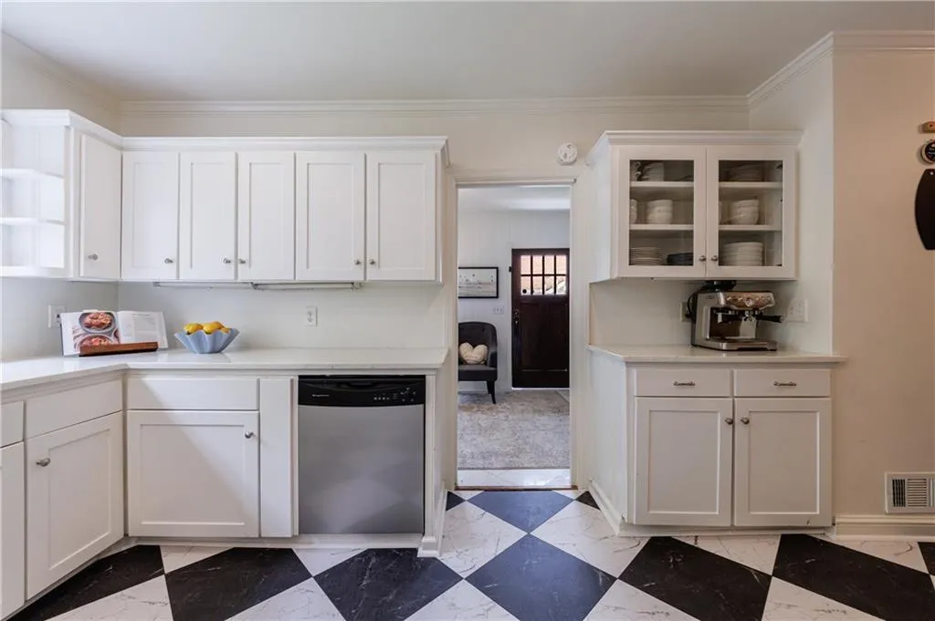Kitchen featuring stainless steel dishwasher, white cabinets, light countertops, open shelves, and ornamental molding