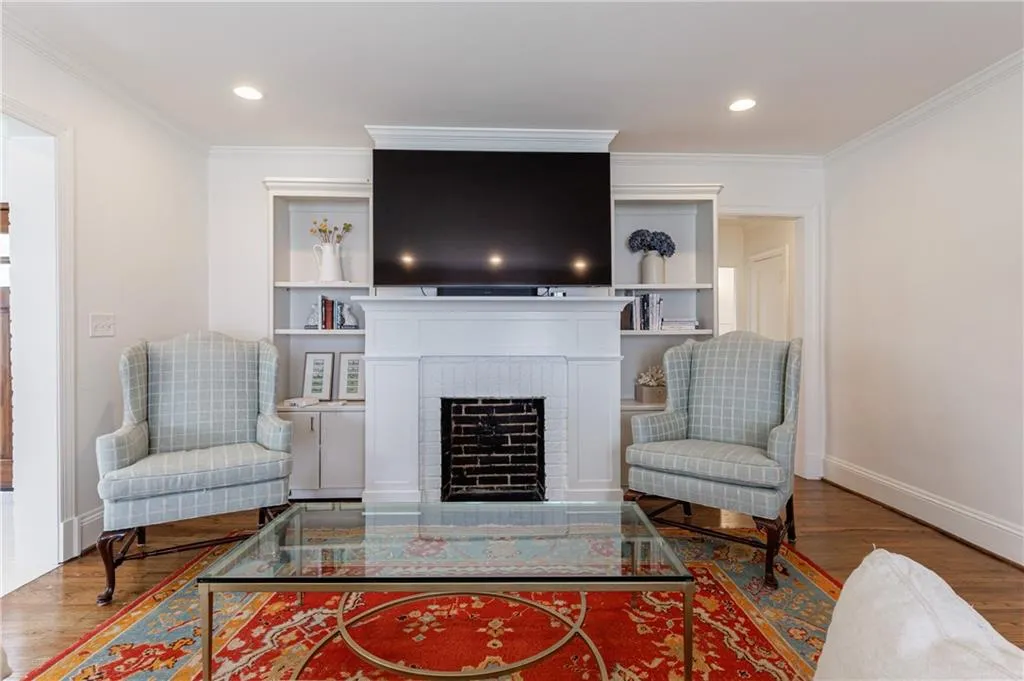 Living area featuring wood finished floors, baseboards, ornamental molding, a fireplace, and recessed lighting