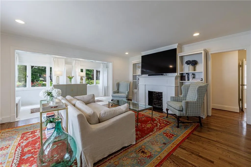 Living area with healthy amount of natural light, wood finished floors, ornamental molding, a fireplace, and recessed lighting