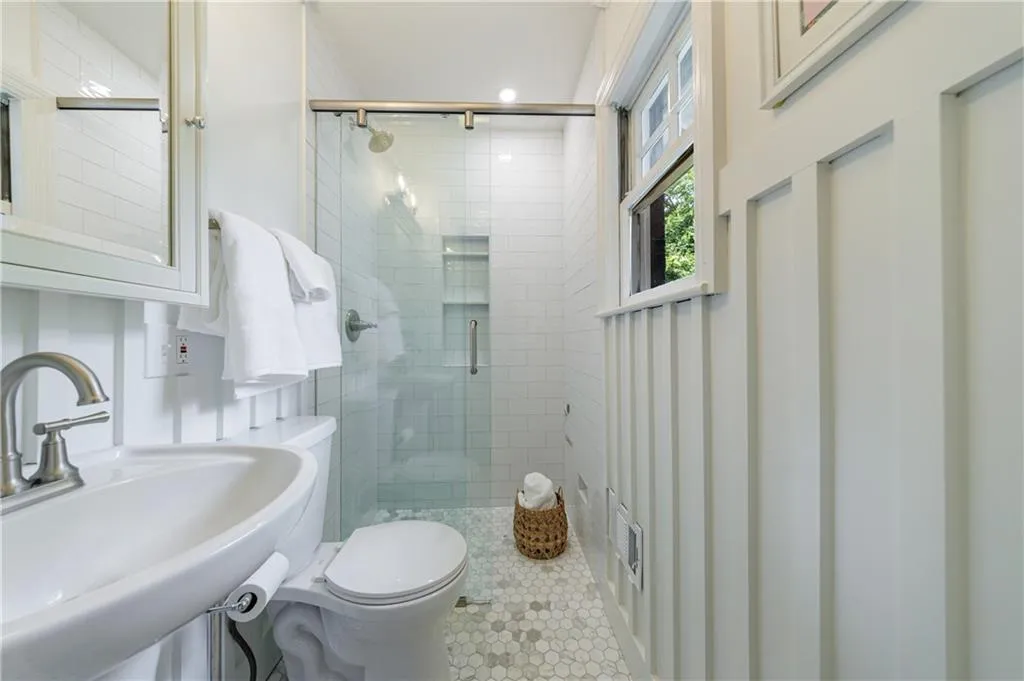 Full bathroom with toilet, a stall shower, a sink, and tile patterned flooring