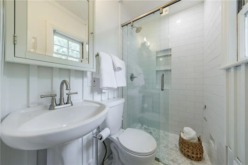 Bathroom with ornamental molding, a shower stall, toilet, and a sink