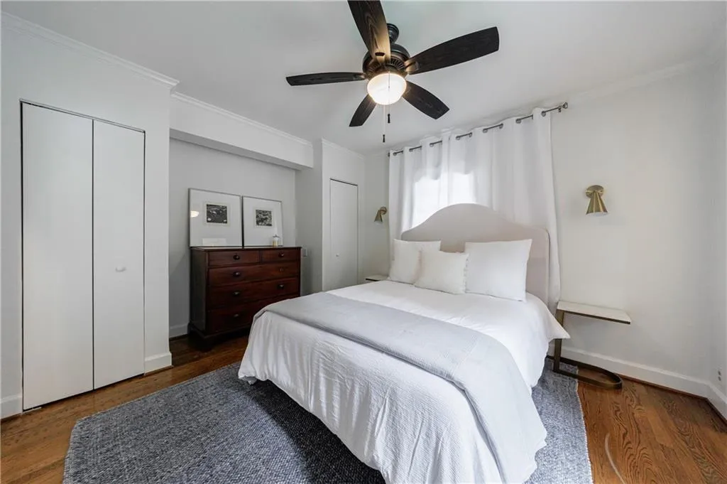 Bedroom featuring multiple closets, crown molding, wood finished floors, baseboards, and ceiling fan