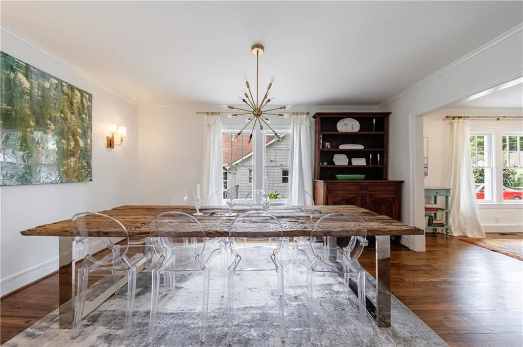 Dining room with wood finished floors, ornamental molding, a chandelier, and baseboards