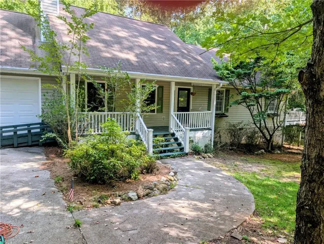 Siding exterior with a covered porch, white railing, and an attached garage