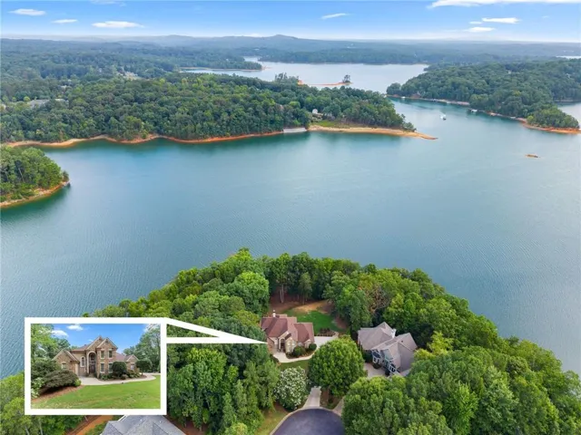 Waterfront property featuring a stone and siding exterior, a multi-car driveway, and mature landscaping