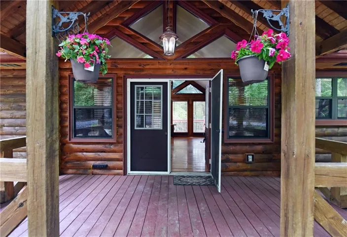 Log cabin exterior featuring a covered porch, wood-finish decking, and exposed wooden beams