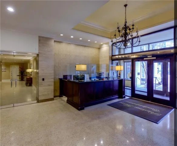 Lobby featuring a dark wood reception desk, polished stone flooring, recessed lighting, and a decorative chandelier