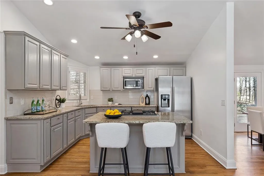 Kitchen featuring gray cabinets, ceiling fan, lofted ceiling, a center island, and stainless steel appliances