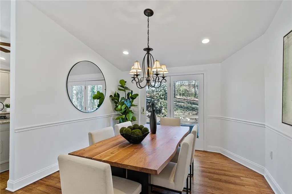 Dining room with wood finished floors, vaulted ceiling, and suspended lighting