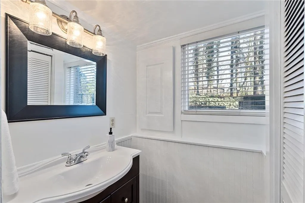 Bathroom with vanity, a closet, and wainscoting