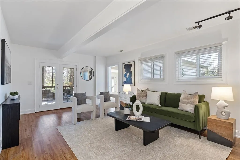 Living room featuring french doors, light wood-style flooring, beamed ceiling, and track lighting