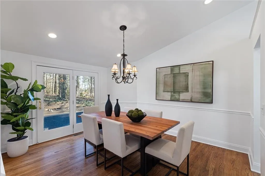 Dining area featuring dark wood-type flooring, vaulted ceiling, and a chandelier