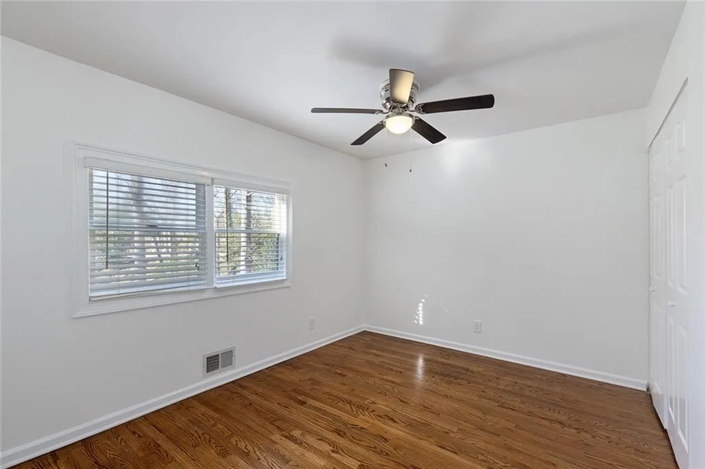 Unfurnished bedroom featuring a closet, dark wood-style floors, and a ceiling fan