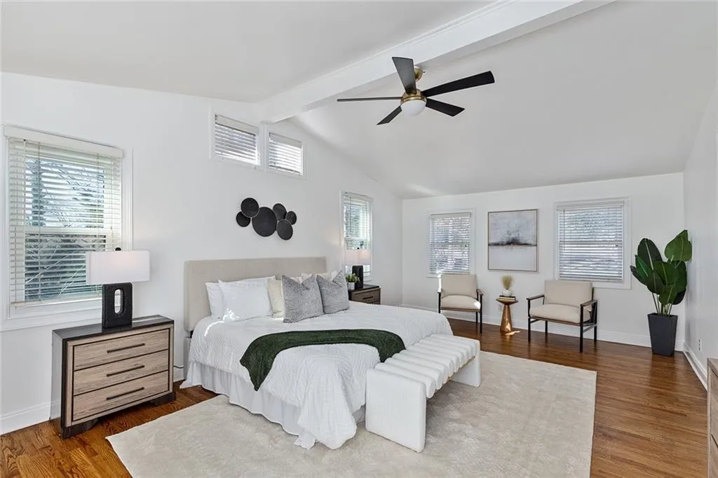 Bedroom with dark wood-style floors, ceiling fan, and vaulted ceiling with beams