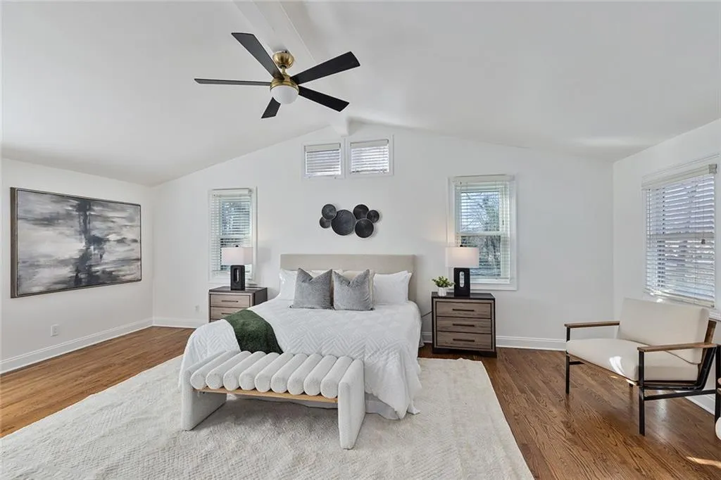 Bedroom with beamed ceiling, wood finished floors, and ceiling fan