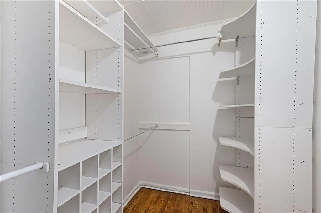 Walk in closet with dark wood-style floors