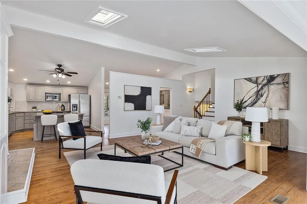 Living room with vaulted ceiling with beams, a ceiling fan, light wood-type flooring, and recessed lighting