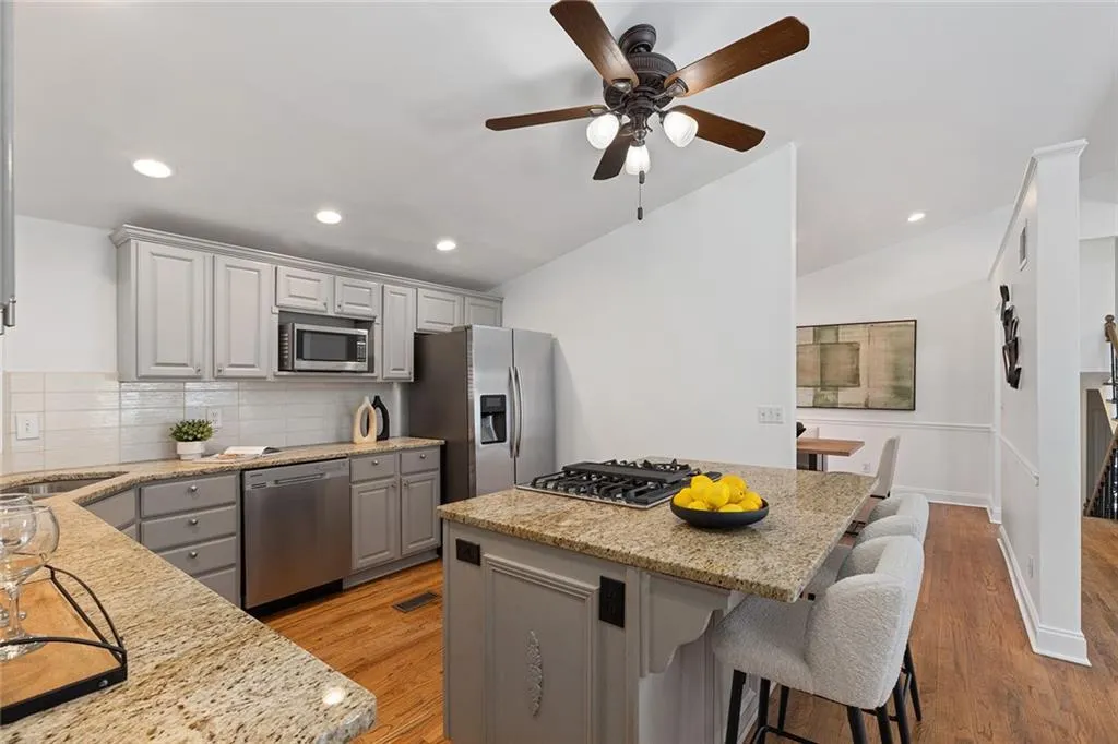Kitchen featuring gray cabinetry, a center island, light stone counters, stainless steel appliances, and a breakfast bar