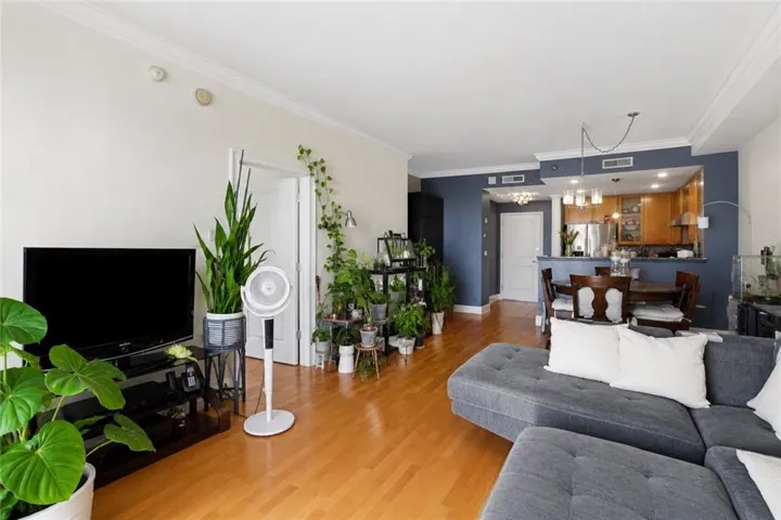 Open-concept living area featuring wood-finish flooring and crown molding