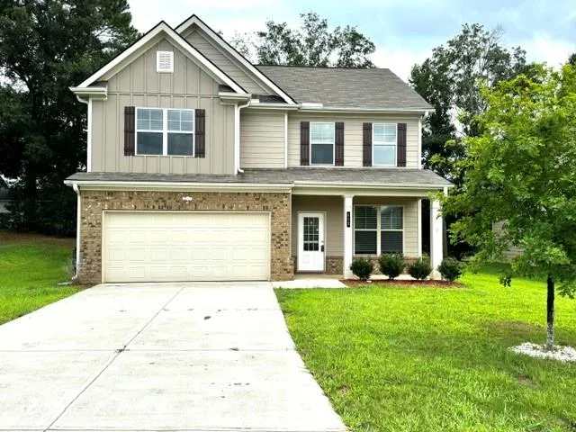 Two-story residence featuring a combination of brick and siding, a covered front porch, an attached two-car garage, a concrete driveway, and mature landscaping