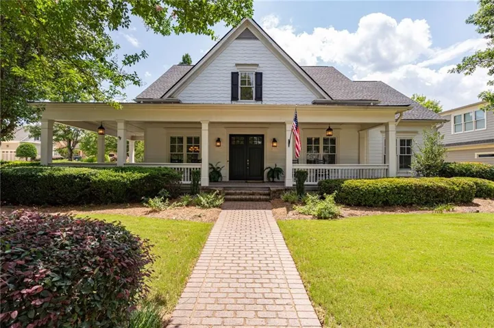 White siding residence featuring a covered front porch with column supports and a brick paver walkway