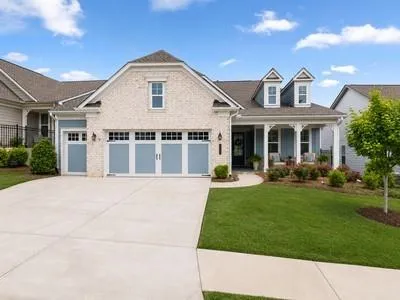 Light-colored brick and siding exterior with a covered front porch featuring white columns