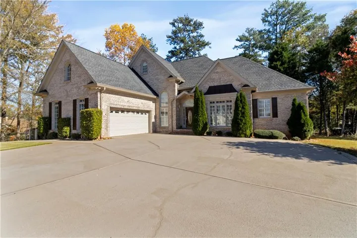French provincial home with brick siding, a shingled roof, driveway, and an attached garage