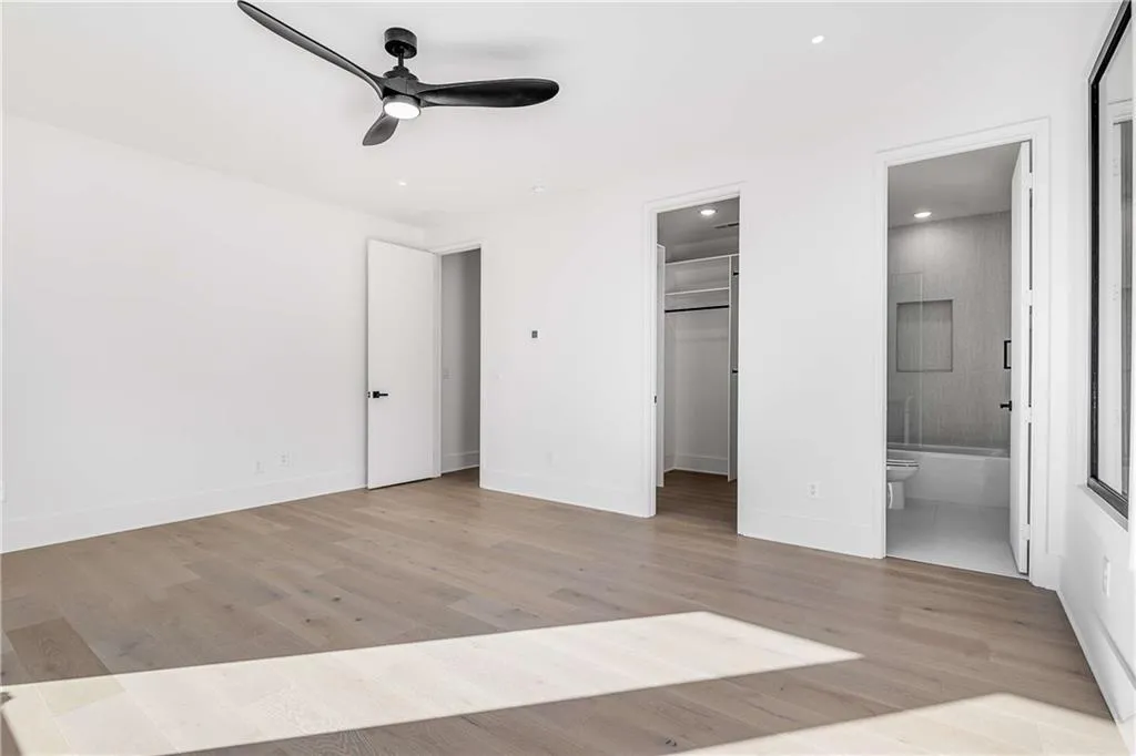 Unfurnished bedroom featuring light wood-style flooring, a walk in closet, recessed lighting, ceiling fan, and ensuite bath