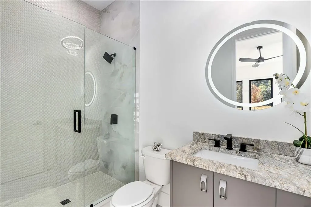 main floor guest Bathroom featuring vanity, a shower stall, and a ceiling fan