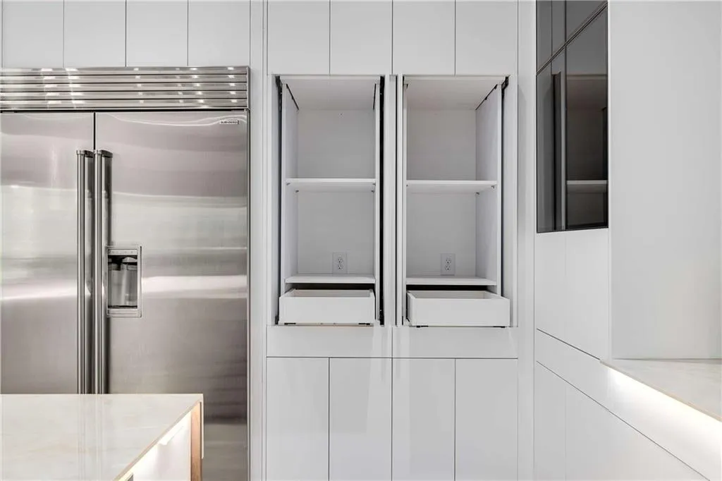 Kitchen view of built in refrigerator, white cabinets, and modern cabinets