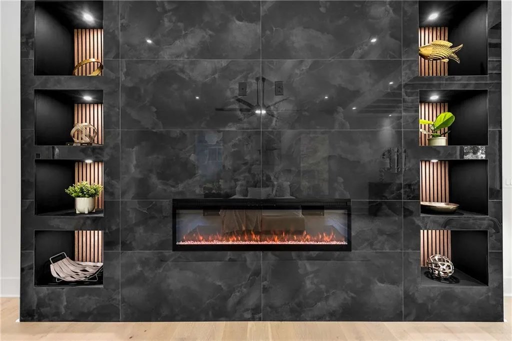 Detailed view of a glass covered fireplace, wood finished floors, and built in shelves