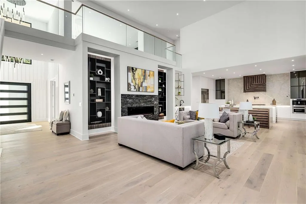 Living room featuring a towering ceiling, light wood finished floors, built in features, recessed lighting, and a fireplace