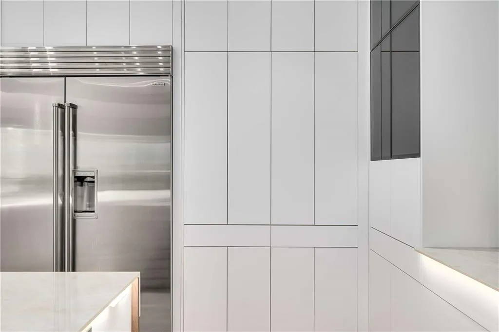 Kitchen view of built in refrigerator, white cabinetry, and light countertops
