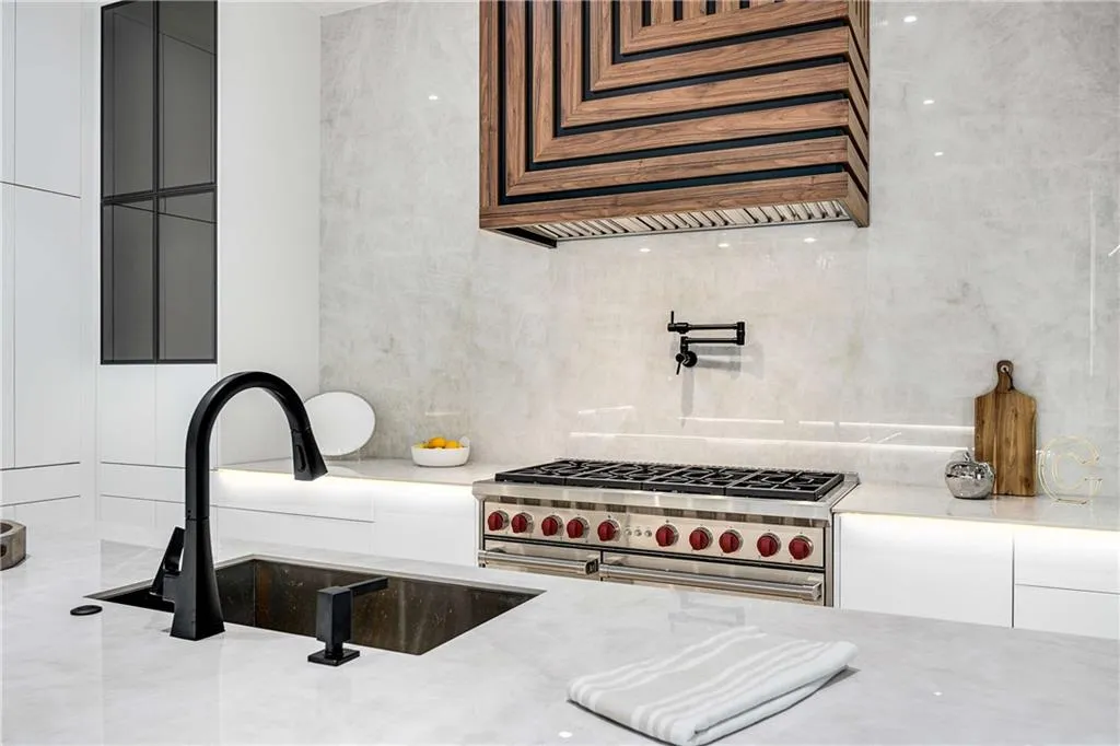 Kitchen featuring range with two ovens, light stone countertops, white cabinetry, custom exhaust hood, and decorative backsplash