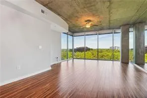 Unfurnished living room with a wall of windows, wood finished floors, and plenty of natural light