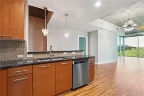 Kitchen with dishwasher, tasteful backsplash, light wood finished floors, dark countertops, and recessed lighting