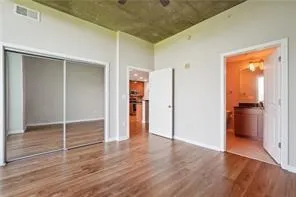 Unfurnished bedroom featuring wood finished floors, a closet, and ensuite bathroom