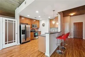 Kitchen with stainless steel appliances, light wood-type flooring, brown cabinets, a peninsula, and recessed lighting