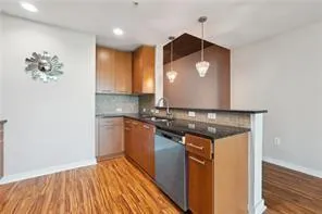 Kitchen with stainless steel dishwasher, a peninsula, tasteful backsplash, dark countertops, and light wood-type flooring