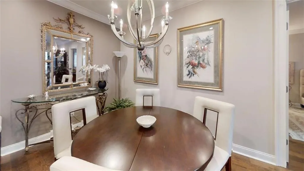 Dining room featuring a chandelier, crown molding, baseboards, and wood finished floors