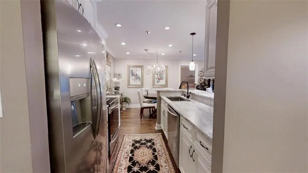 Kitchen with dark wood finished floors, stainless steel appliances, recessed lighting, ornamental molding, and white cabinets