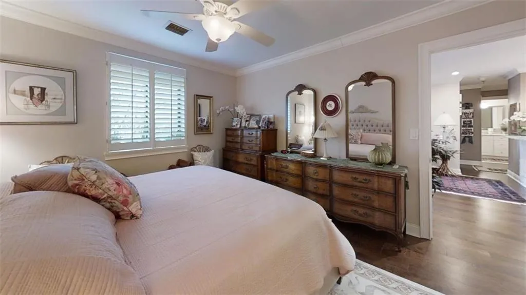 Bedroom featuring baseboards, visible vents, a ceiling fan, wood finished floors, and crown molding