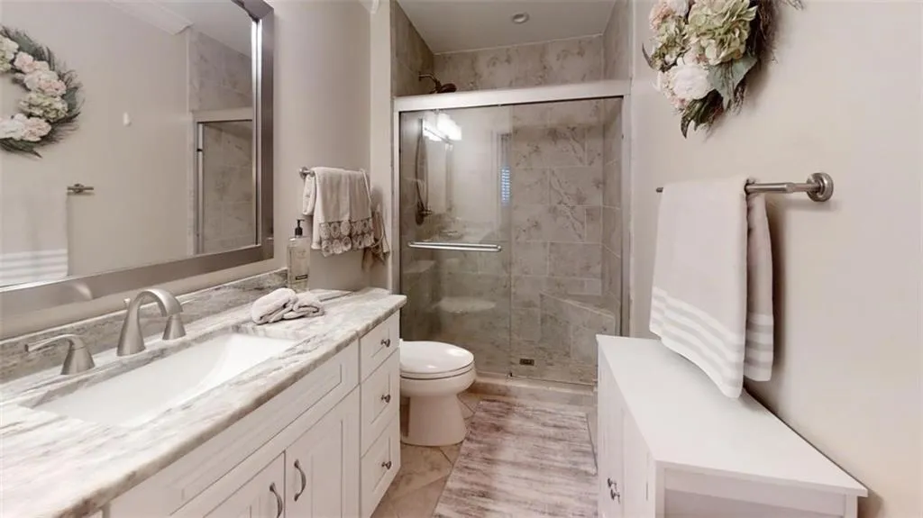 Bathroom featuring a stall shower, vanity, and toilet