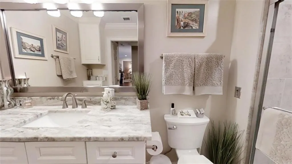 Bathroom with toilet, visible vents, ornamental molding, and vanity