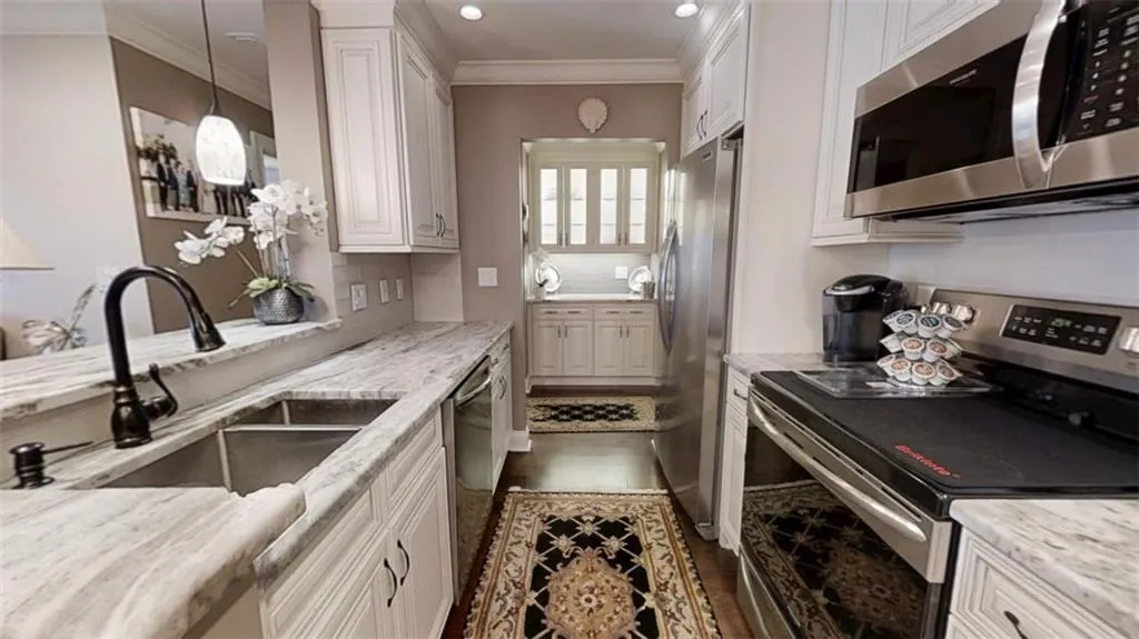 Kitchen featuring tasteful backsplash, dark wood-style flooring, stainless steel appliances, crown molding, and a sink