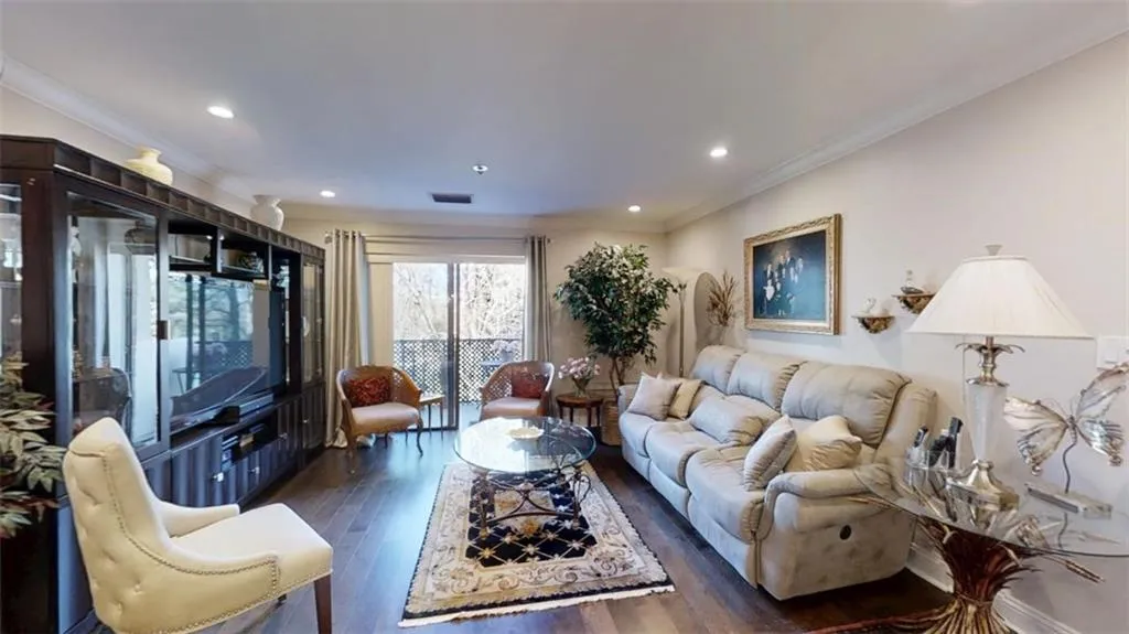 Living area featuring dark wood-style floors, recessed lighting, visible vents, and ornamental molding