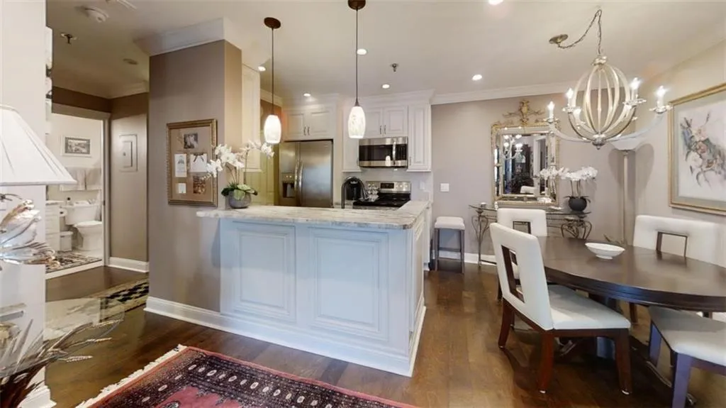 Kitchen featuring a chandelier, appliances with stainless steel finishes, dark wood-type flooring, a peninsula, and white cabinetry