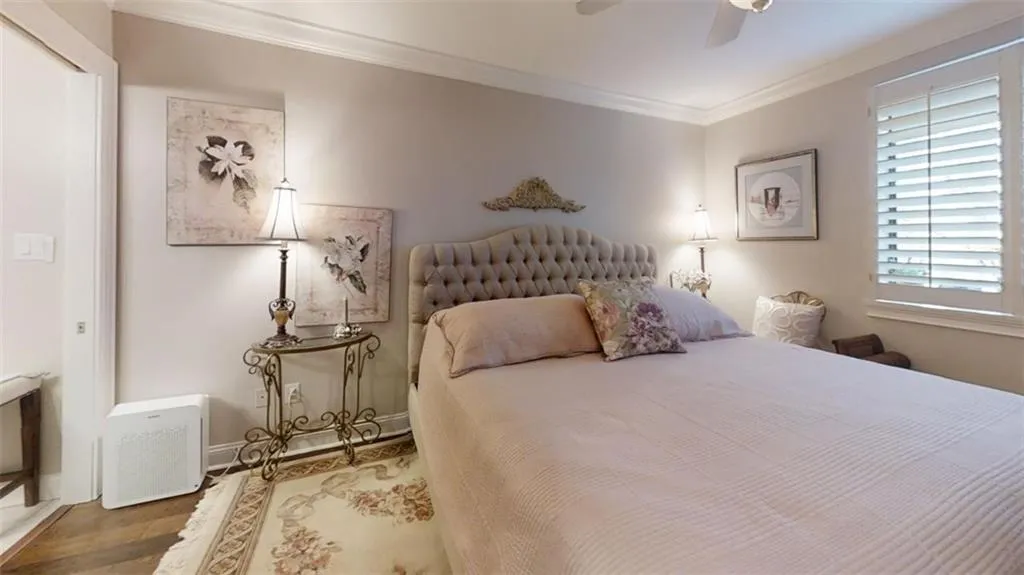 Bedroom with ceiling fan, baseboards, crown molding, and wood finished floors