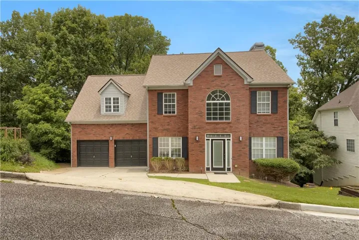 Brick exterior with a peaked roofline, featuring an arched window, a front entry with sidelights, and a two-car garage
